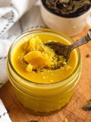 A jar of golden Niter Kibbeh with a spoon scooping it.