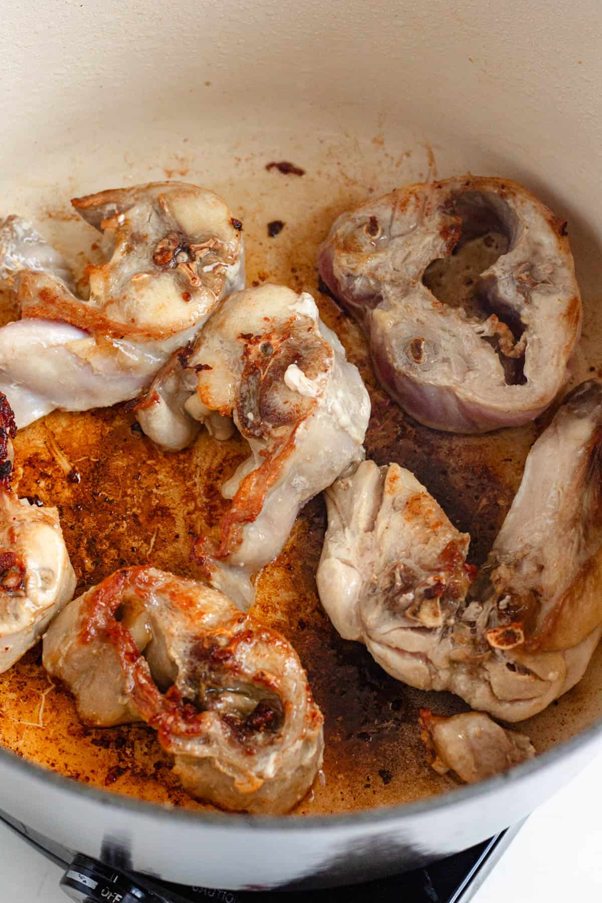 Rabbit pieces browning in hot oil inside a Dutch oven, seared on all sides until golden brown.