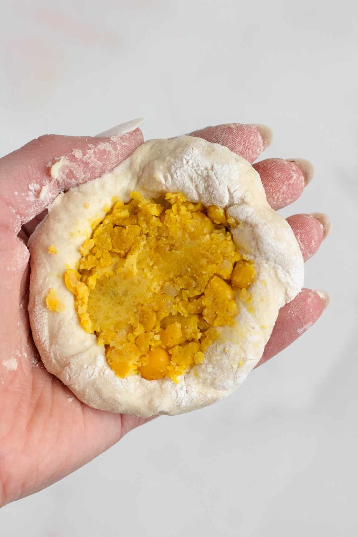 Dough balls being filled with a savory pea mixture.