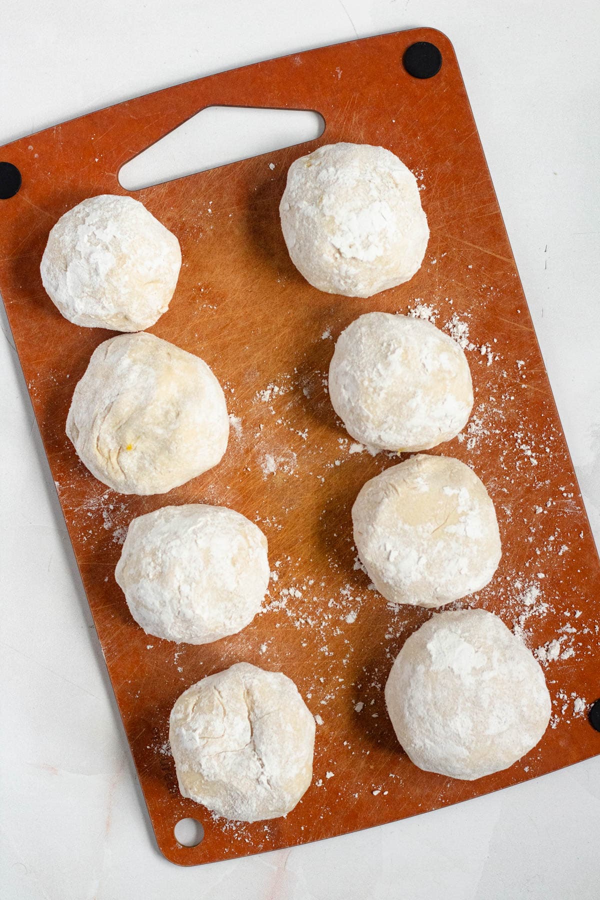 Dough balls neatly lined up on a board.