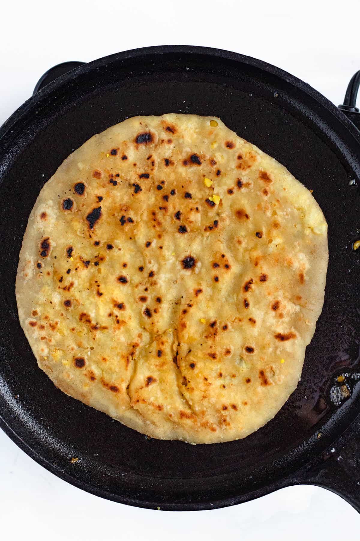Golden, cooked Dhal Puri resting on the griddle, ready to serve.