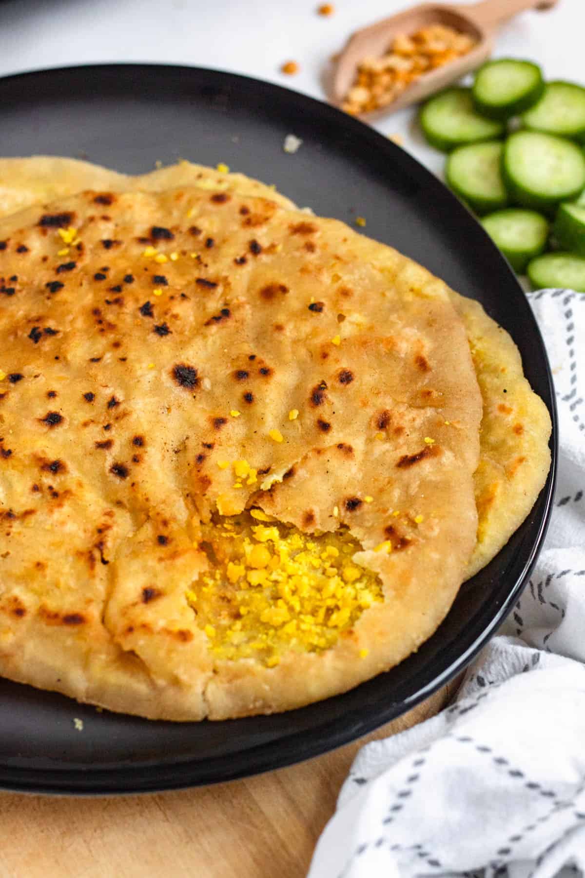 Golden-brown Golden-brown Dhal Puri (Soft Split Pea Flatbread) on a plate, torn open to reveal a yellow pea filling.