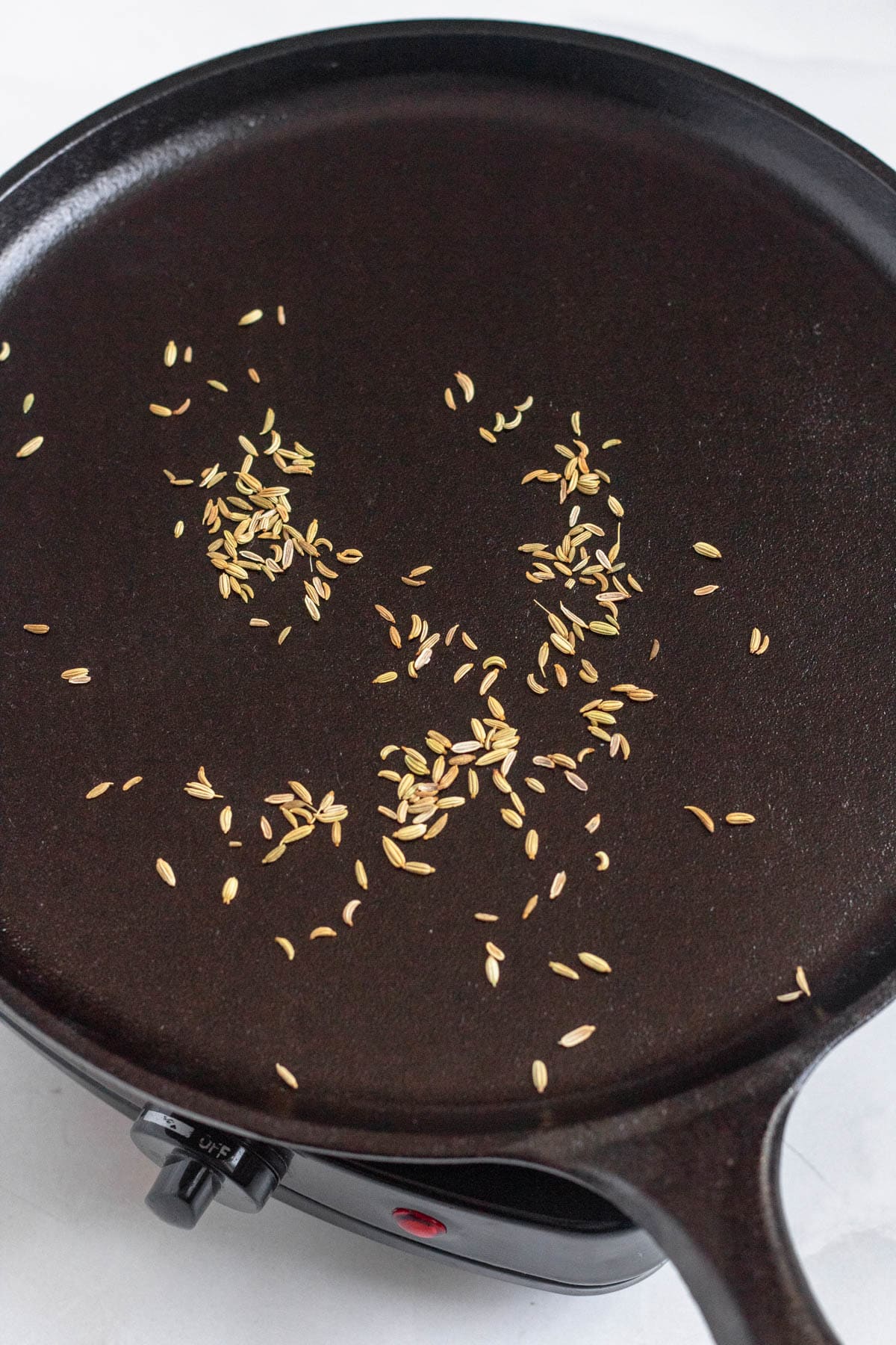 Fennel seeds toasting in a pan.