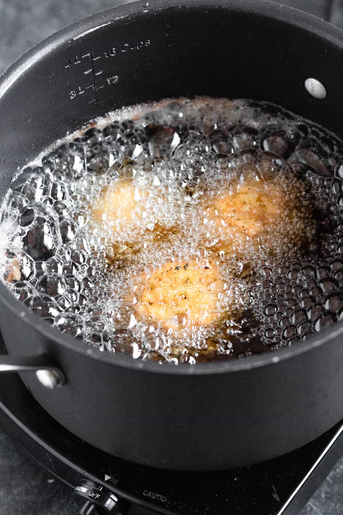 Arancini frying in hot oil until golden and crispy.