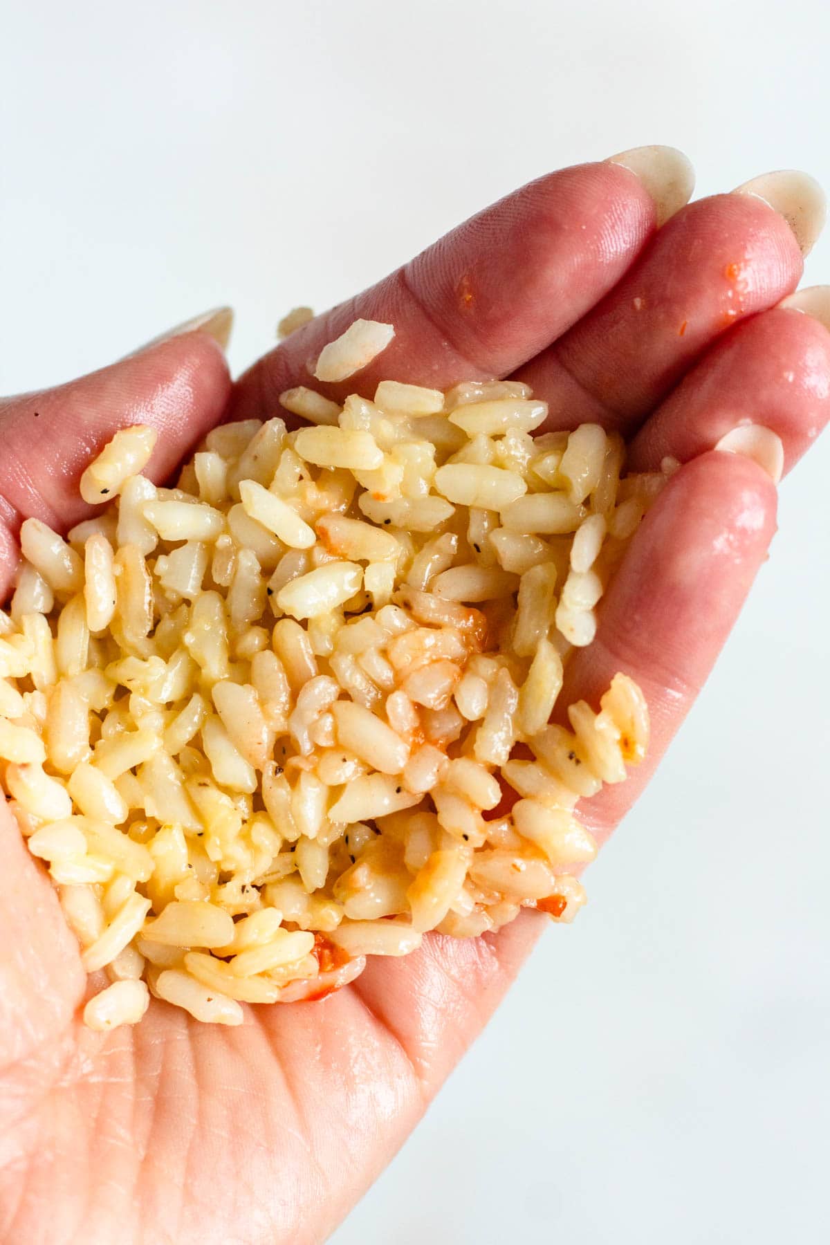 Cooked rice held in a hand, ready to be shaped.