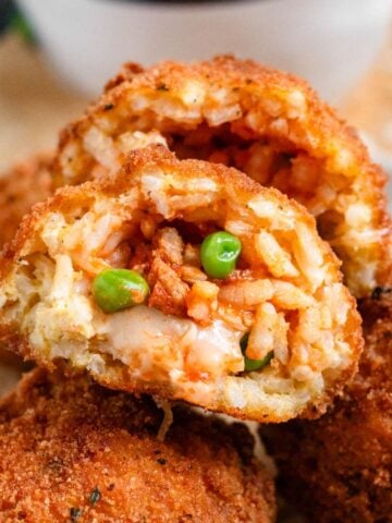 Crispy golden Arancini with green peas and mozzarella filing.