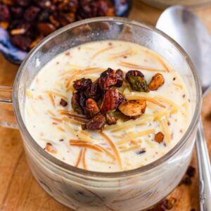 Creamy vermicelli porridge topped with toasted nuts and raisins in a glass cup.