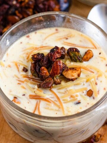 Creamy vermicelli porridge topped with toasted nuts and raisins in a glass cup.