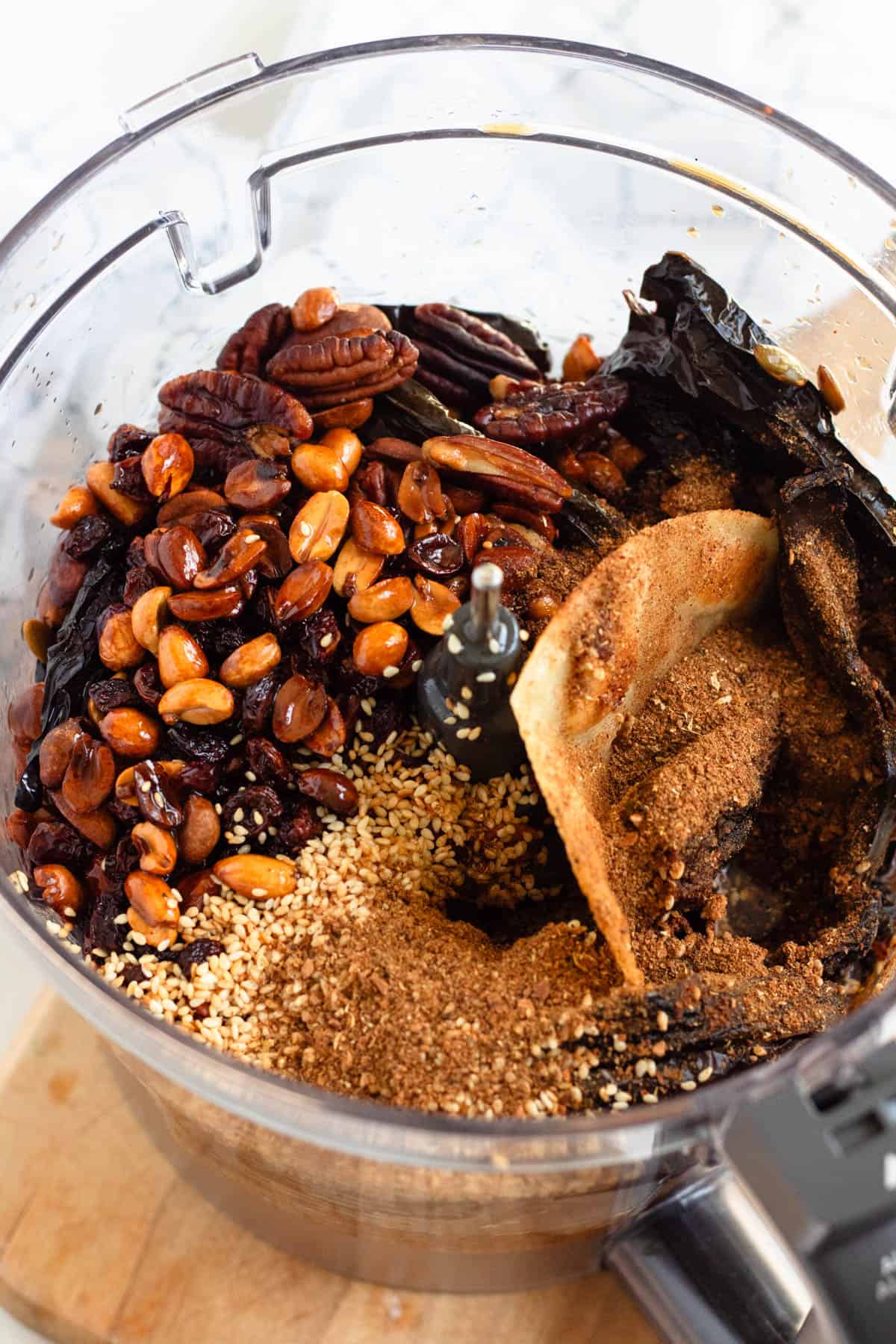 Mole ingredients including chiles, nuts, seeds, and spices in a food processor ready to blend.
