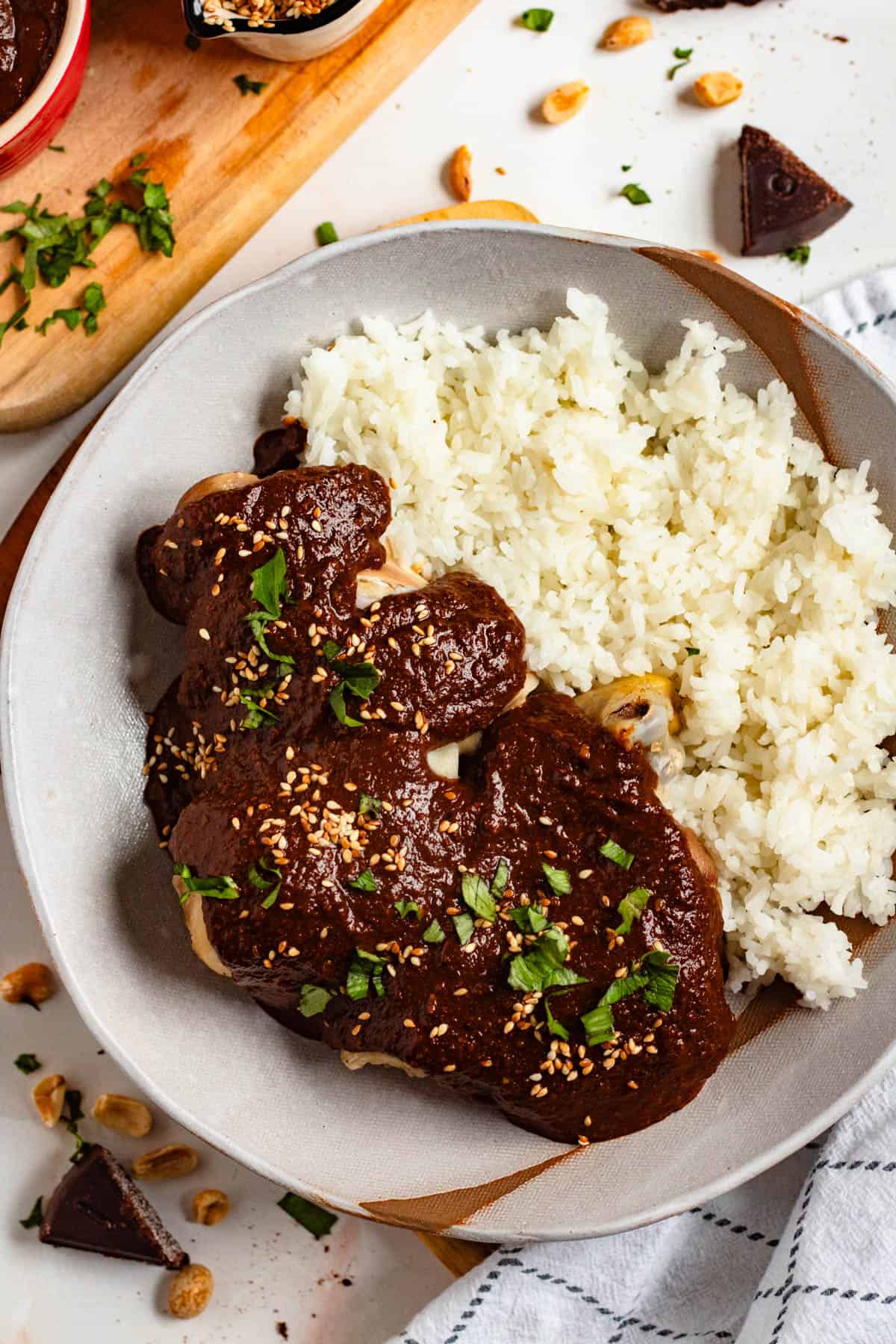 Mole poblano chicken topped with sesame seeds and herbs, served with white rice.