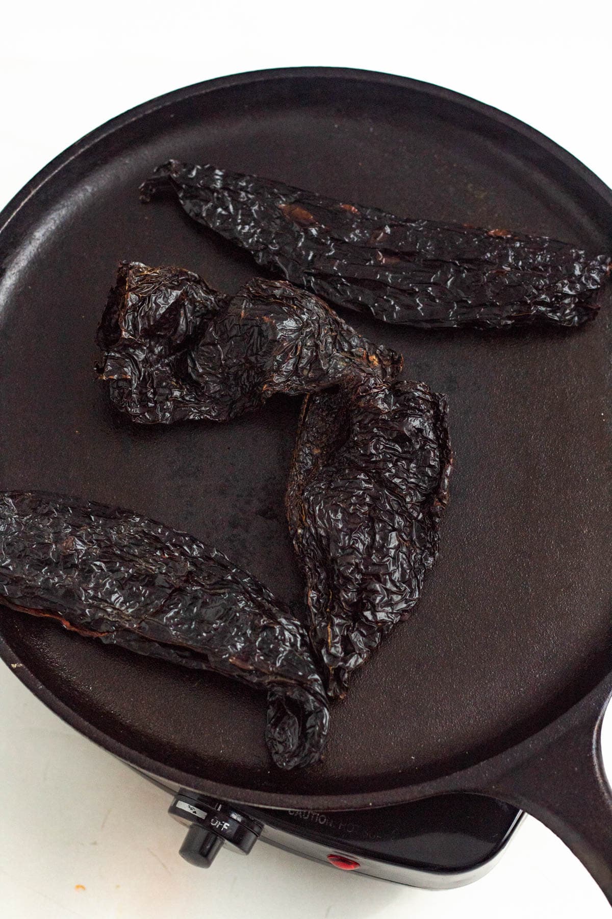 Dried chiles toasted on a skillet.