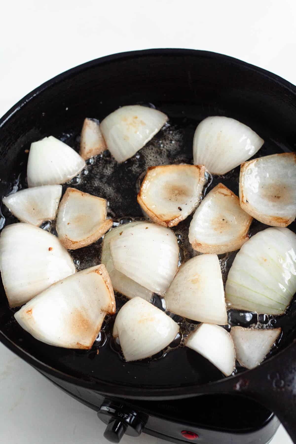 Onion chunks lightly charred in a skillet.