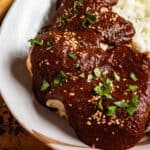 Chicken in mole poblano sauce topped with sesame seeds and herbs, served with rice.