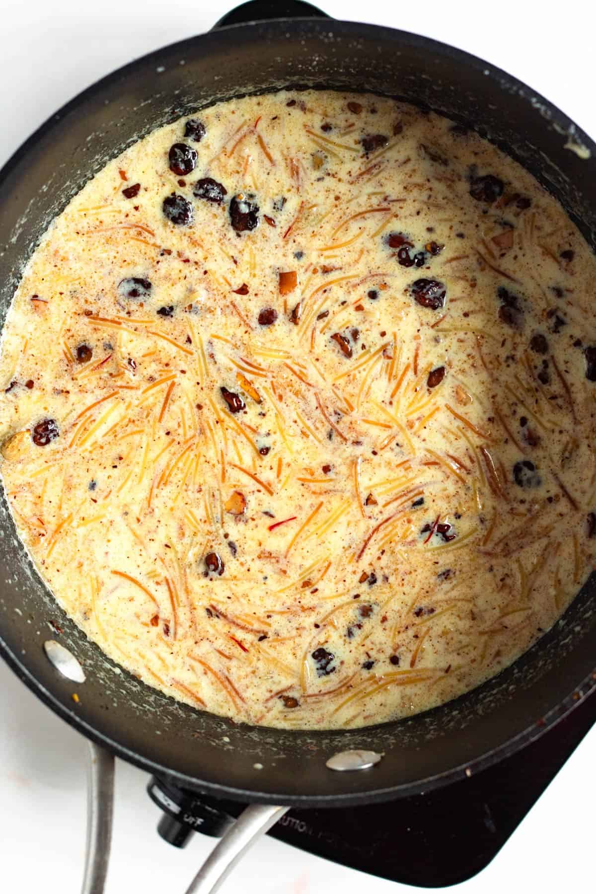 Toasted vermicelli added to simmering saffron milk in a pot.