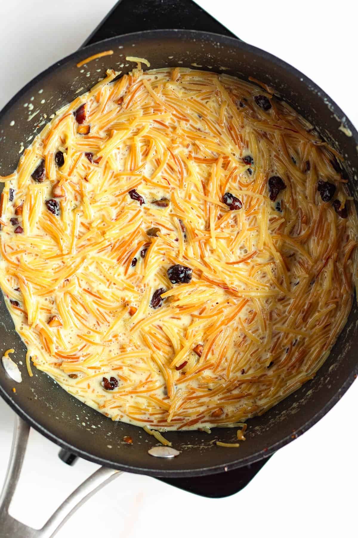 Creamy vermicelli porridge cooking with raisins and nuts in the pot.