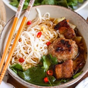 Savory Bún Chả with juicy grilled pork, vermicelli noodles, fresh herbs, and red chilies, ready to serve.