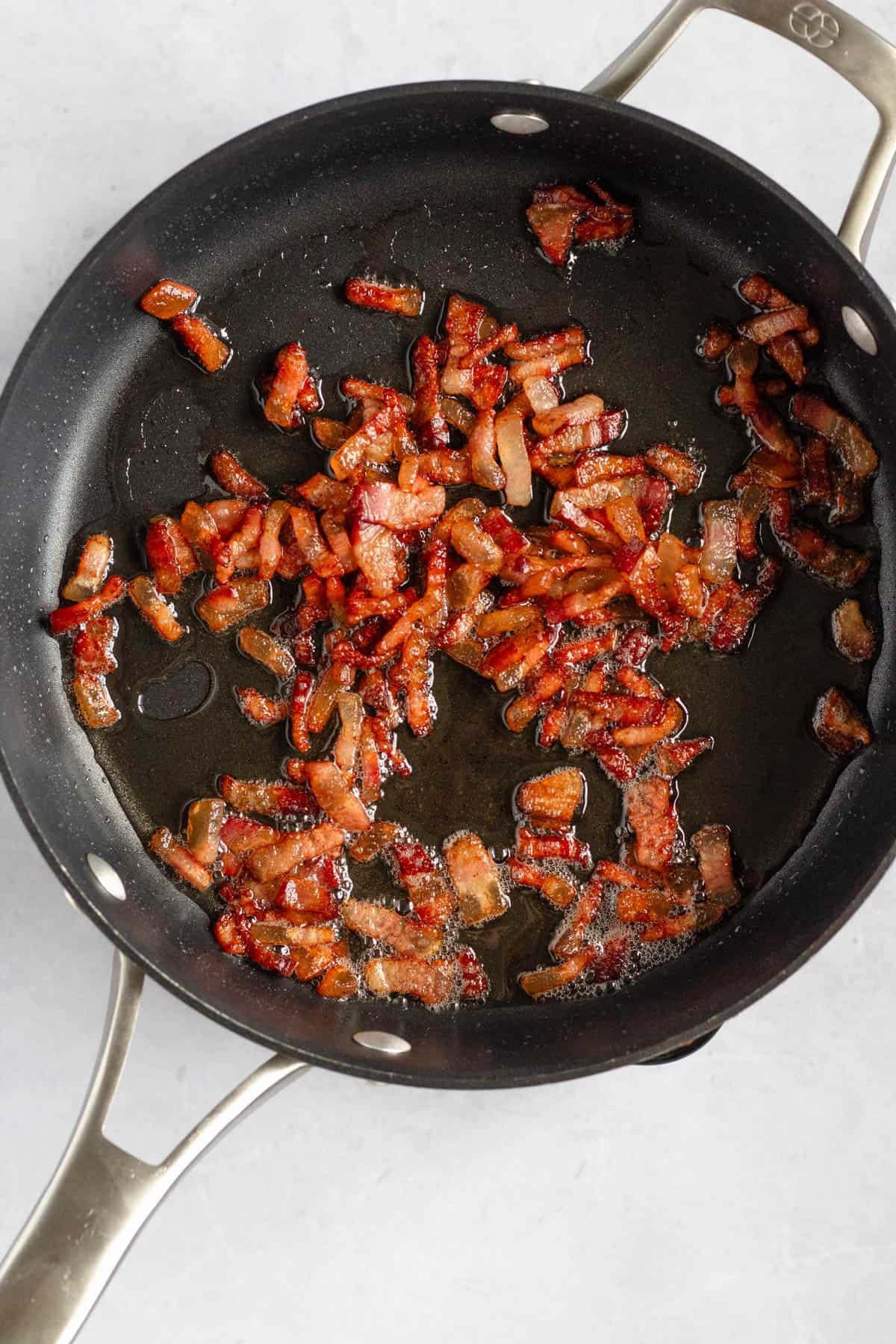 Crispy guanciale cooking in a pan for Bucatini all’Amatriciana.