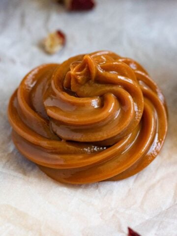 Thick homemade dulce de leche piped into a glossy caramel swirl.