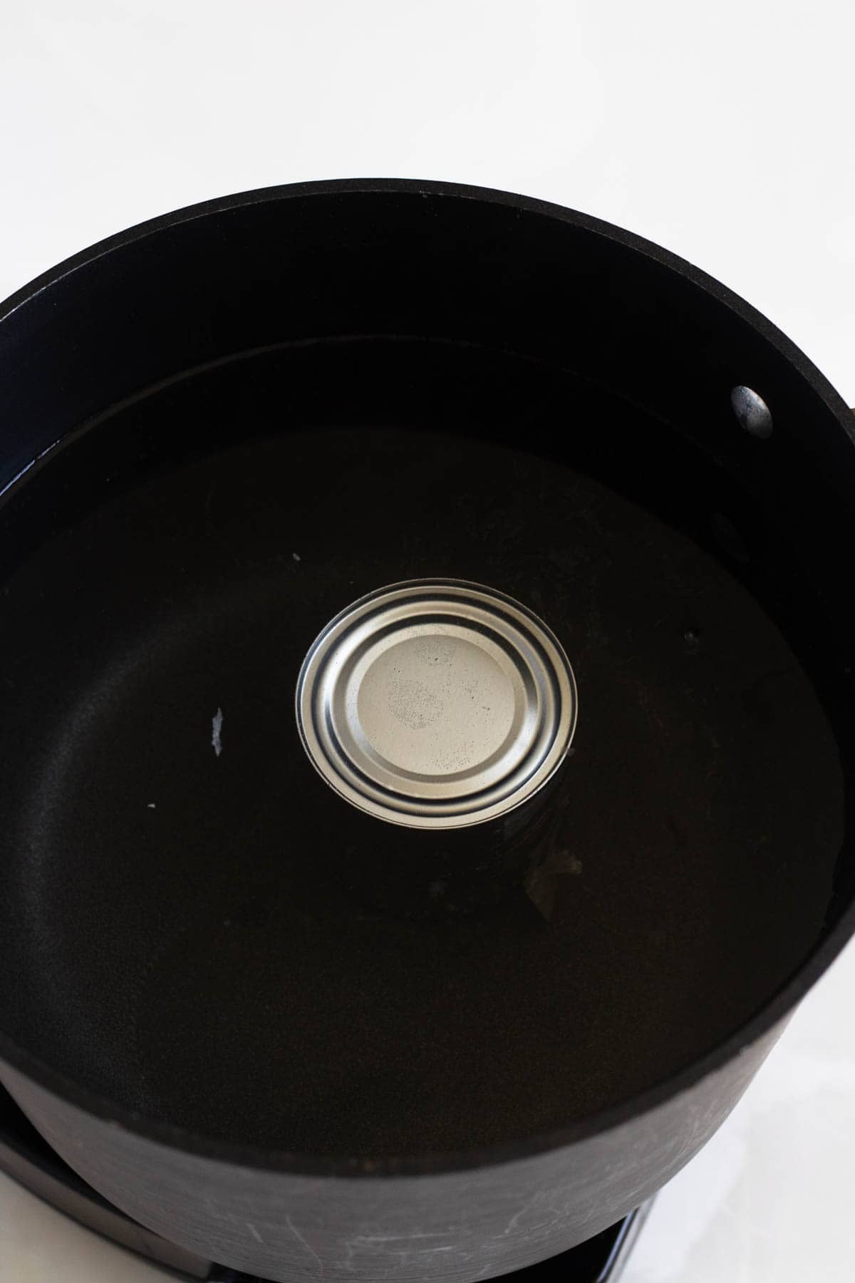 Stovetop dulce de leche can simmering fully submerged in water.
