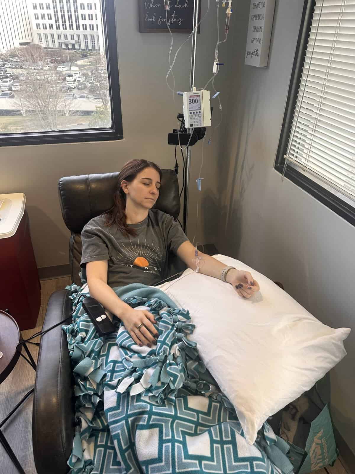 A girl sleeping in a chair while getting an infusion.