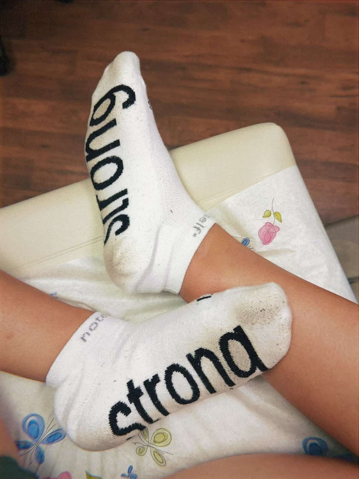 Two feet wearing socks that say the word Strong on a doctor table. 