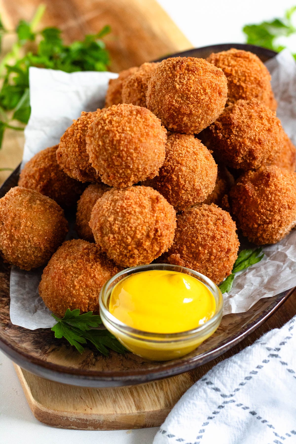 A pile of Bitterballen on a tray with mustard in front of them.