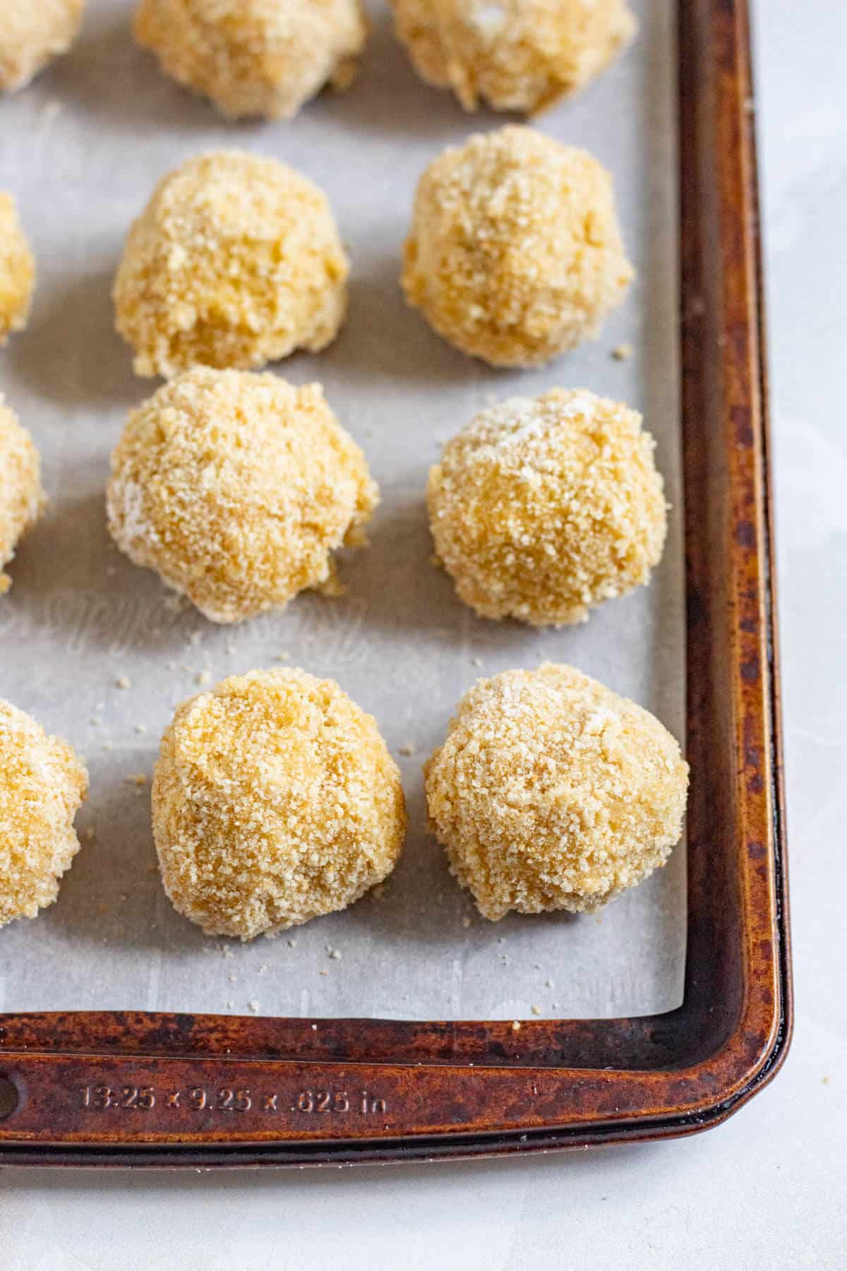 Breadcrumb-coated bitterballen lined up on a tray and ready to fry.