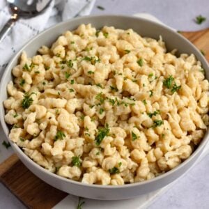 Homemade German spaetzle served in a bowl with butter and fresh parsley.