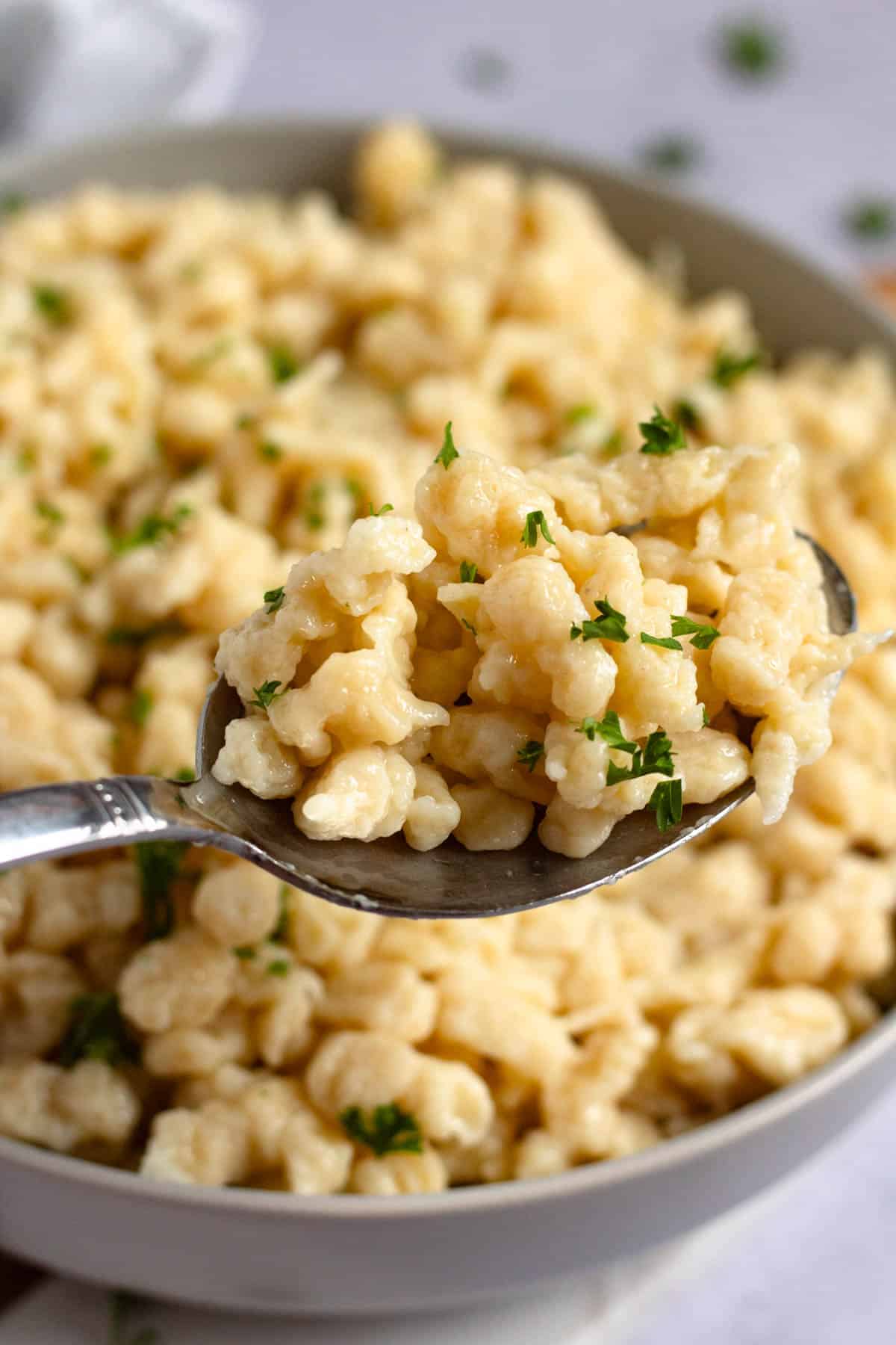 Tender homemade spaetzle with butter and parsley served on a spoon.